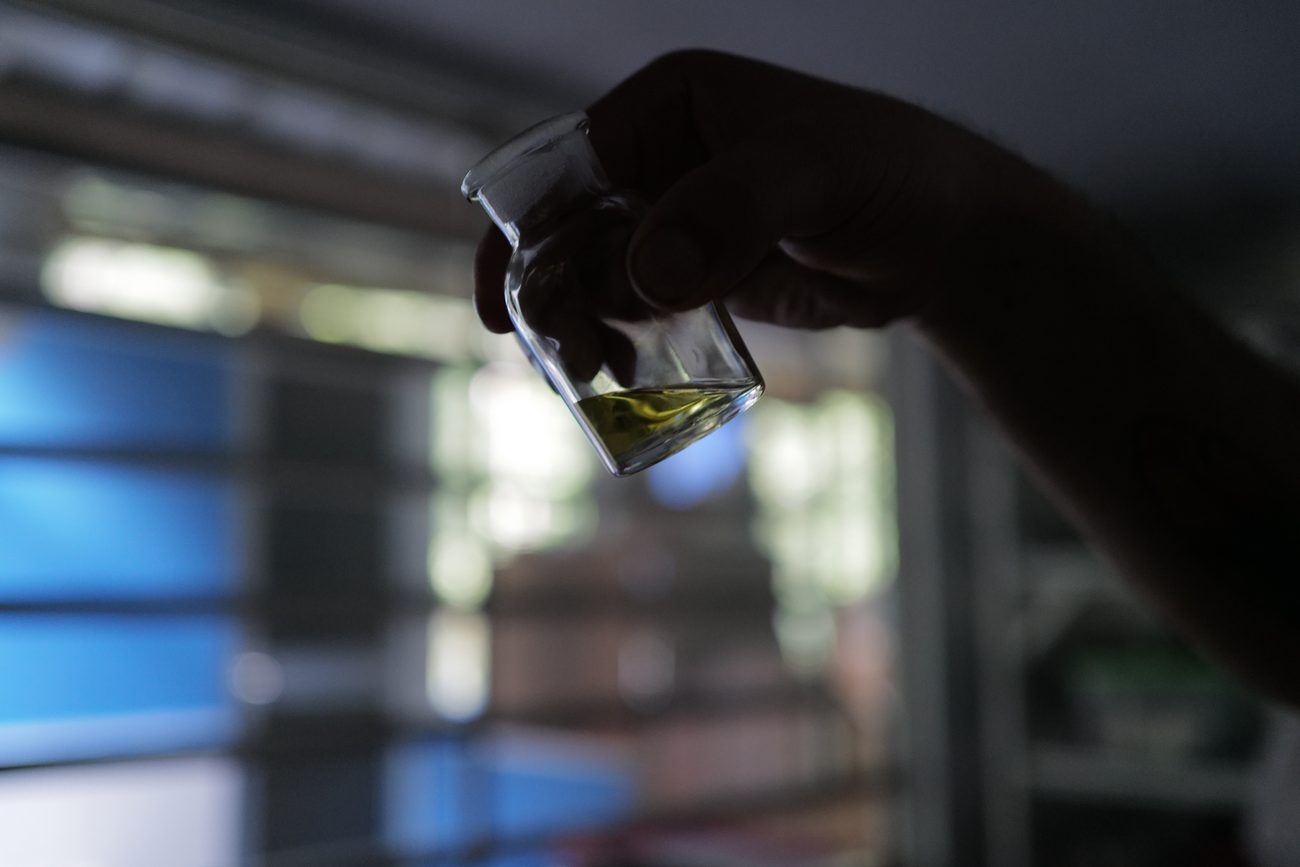 A vial of the first pressing held against the light